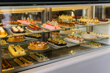 Showcase with sweets, Various desserts and cakes for sale in the pastry shop. Glass display at store bakery pastry shop.