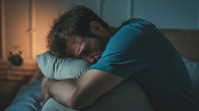 A missleeped man laying in bed holds a pillow, providing comfort and support while resting.