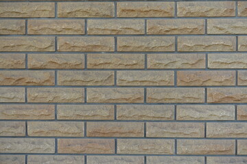 Background - beige brick veneer wall with grey mortar joints