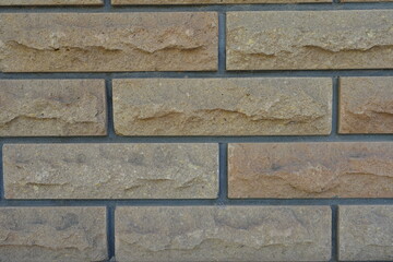Close view of beige brick veneer wall with grey mortar joints