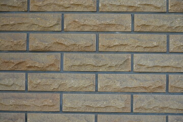 Dusty surface of beige brick veneer wall with grey mortar joints