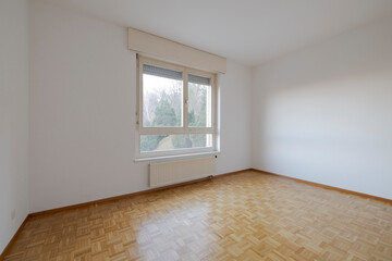 Empty bedroom with parquet and a window through which lots of light enters