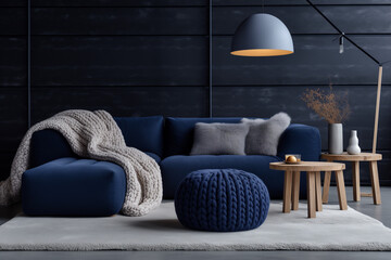 Two knitted poufs near dark blue corner sofa. Scandinavian home interior design of modern living room