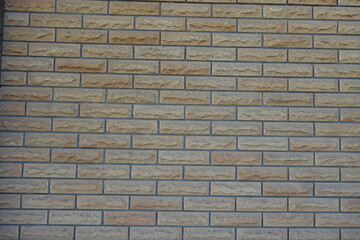Surface of beige brick veneer wall with grey mortar joints