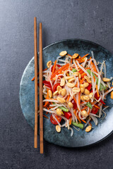Green Papaya Salad, som tam thai on black slate background. Top view