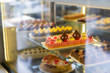 Showcase with sweets, Various desserts and cakes for sale in the pastry shop. Glass display at store bakery pastry shop.