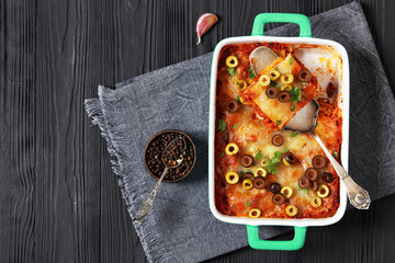 lasagna with olive rings in green baking dish