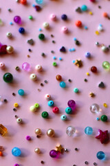 Various colorful beads on bright pink background. Selective focus.