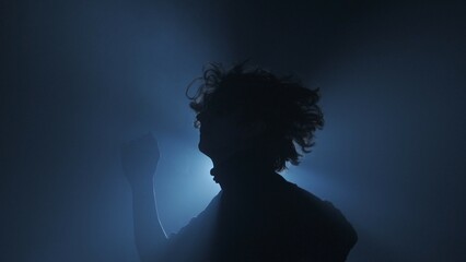 Male model against bright light on black background in studio. Man clubber silhouette dancing...
