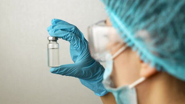 Female doctor holding vaccine ampoule in hand, 4k