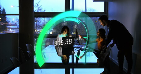 Image of green speedometer over diverse businesspeople using laptops
