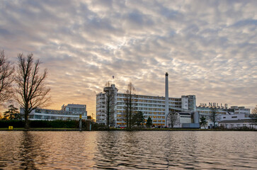 View across Schie canal towards Unesco world heritage Van Nelle factory, now an office building and event location under a dramatic sky at sunset