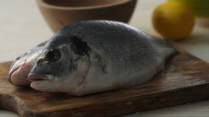 Raw Fresh Orada Fish on a Wooden Cutting Board. Selective focus, close-up.