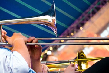 close-up of the hands of a street musician holding a gold-colored pump-action trumpet	
