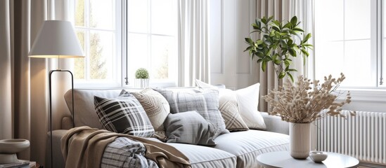 Light living room with a grey sofa, cozy pillows, plaid, and a lamp by the window.