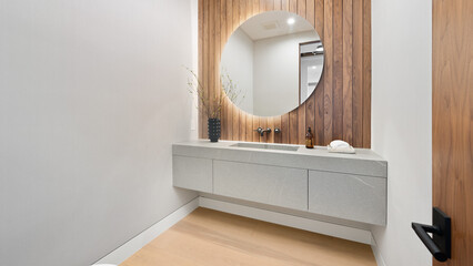 Contemporary bathroom with circular mirror atop sink and countertop