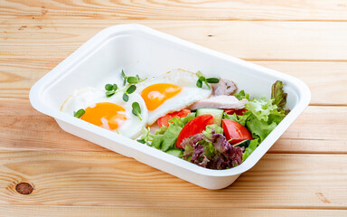 Fried eggs and turkey. Healthy diet. Takeaway food.  On a wooden background.