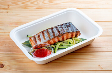 Grilled pink salmon on a bed of zucchini. Healthy food. Takeaway food.  On a wooden background.