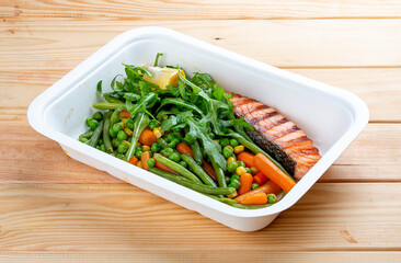 Salmon with blanched vegetables. Healthy diet. Takeaway food.  On a wooden background.