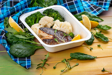 Sea bass fillet, blanched broccoli and cauliflower. Healthly food. Takeaway food. On a wooden...