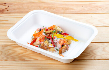 Hake fricassee with vegetables. Healthy diet. Takeaway food.  On a wooden background.