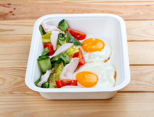 Fried eggs and turkey. Healthy diet. Takeaway food.  On a wooden background.