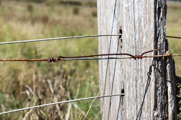 close up of old timber post and wire fence in field
