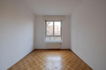 Front view of an empty room with parquet and nature view.