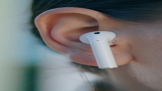 Woman face wireless earbud in ear close up. Portrait girl in headset vetrically 