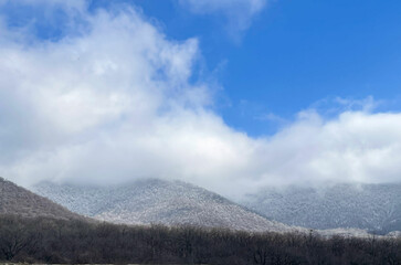 Snowy mountains, blue and cloudy sky, mountain landscape of a village in winter
