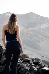 Naklejka na ściany i meble woman standing on her back, looking at the volcano Tajogaite