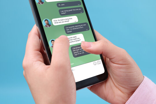 Woman texting with friend using messaging application on smartphone against light blue background, closeup - Powered by Adobe