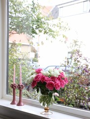 Vase with beautiful bouquet of roses and candles on windowsill indoors