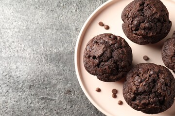 Delicious chocolate muffins on grey textured table, top view. Space for text