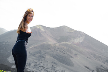 standing woman smiles extends her hand looking at camera in a volcano