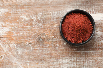 Cranberry powder in bowl on wooden table, top view. Space for text