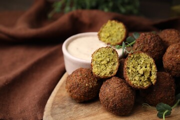 Delicious falafel balls and sauce on table, closeup