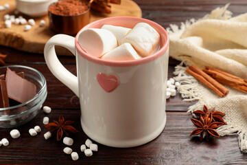Tasty hot chocolate with marshmallows and ingredients on wooden table, closeup