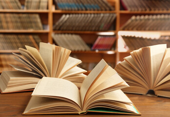 Open books on wooden table in library