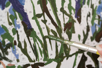 A photo of a picture that is colored by numbers in the process of coloring with a brush