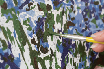 A photo of a picture that is colored by numbers in the process of coloring with a brush