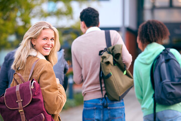 Portrait Of Female University Student Looking Over Shoulder With Friends Outside College Buildings