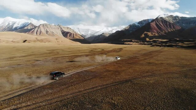 Traveling by two off-road vehicles are driving off-road to high, beautiful and snowcapped mountains. Pamir.  Fantastic mountains of Tajikistan. Road trip of freedom.