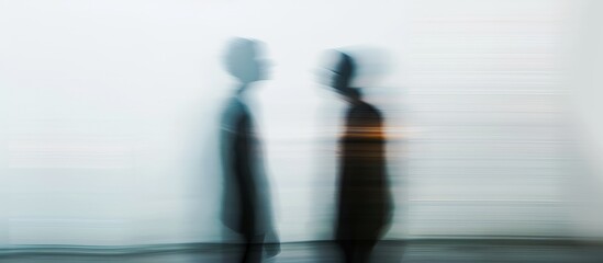 A monochrome photograph of two people standing side by side, their shadows creating blurred and dark figures against a room's horizon. The electric blue tint adds a hint of color.