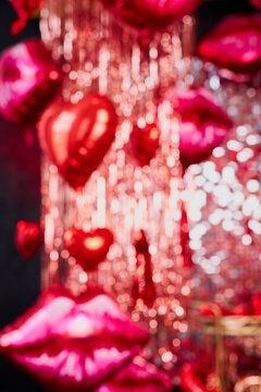 Festive background for valentine's day with copy space. Festive red bokeh of tinsel, balloons and romantic decoration, unfocused