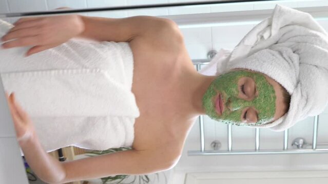 A young woman with a green moisturizing mask on her face suddenly sees herself in the mirror and is frightened.