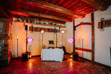 Valmiera, Latvia - July 7, 2023 - DJ booth with colorful stage lights in a rustic room with wooden...