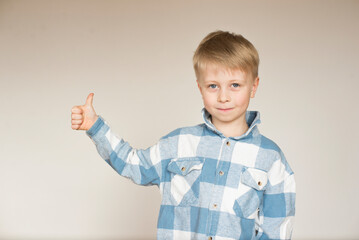 portrait of a cute blond boy, showing thumbs up