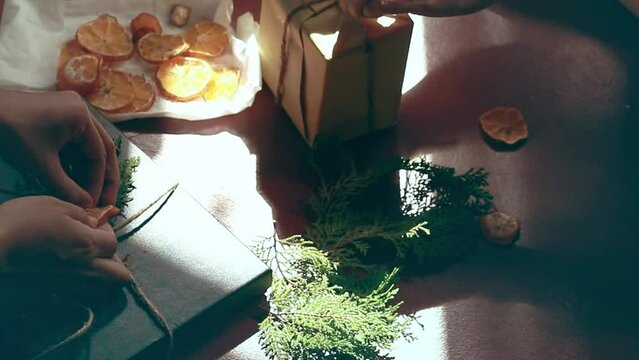 Decorating gift boxes with organic materials like paper, twine, dried citrus slices and pine for a charming rustic and sustainable present for all occasion 