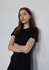Fototapeta premium A sweet woman in a black T-shirt posing on a light background stood in a confident pose